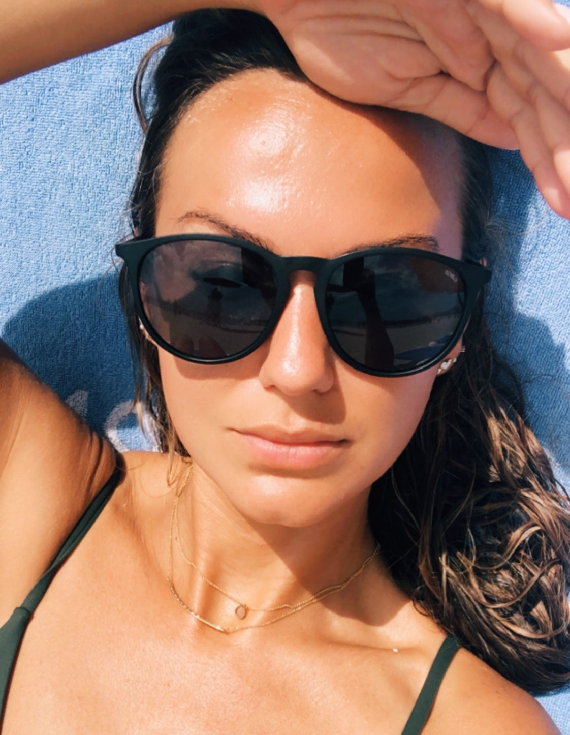 Woman in black sunglasses wearing a green bathing suit.