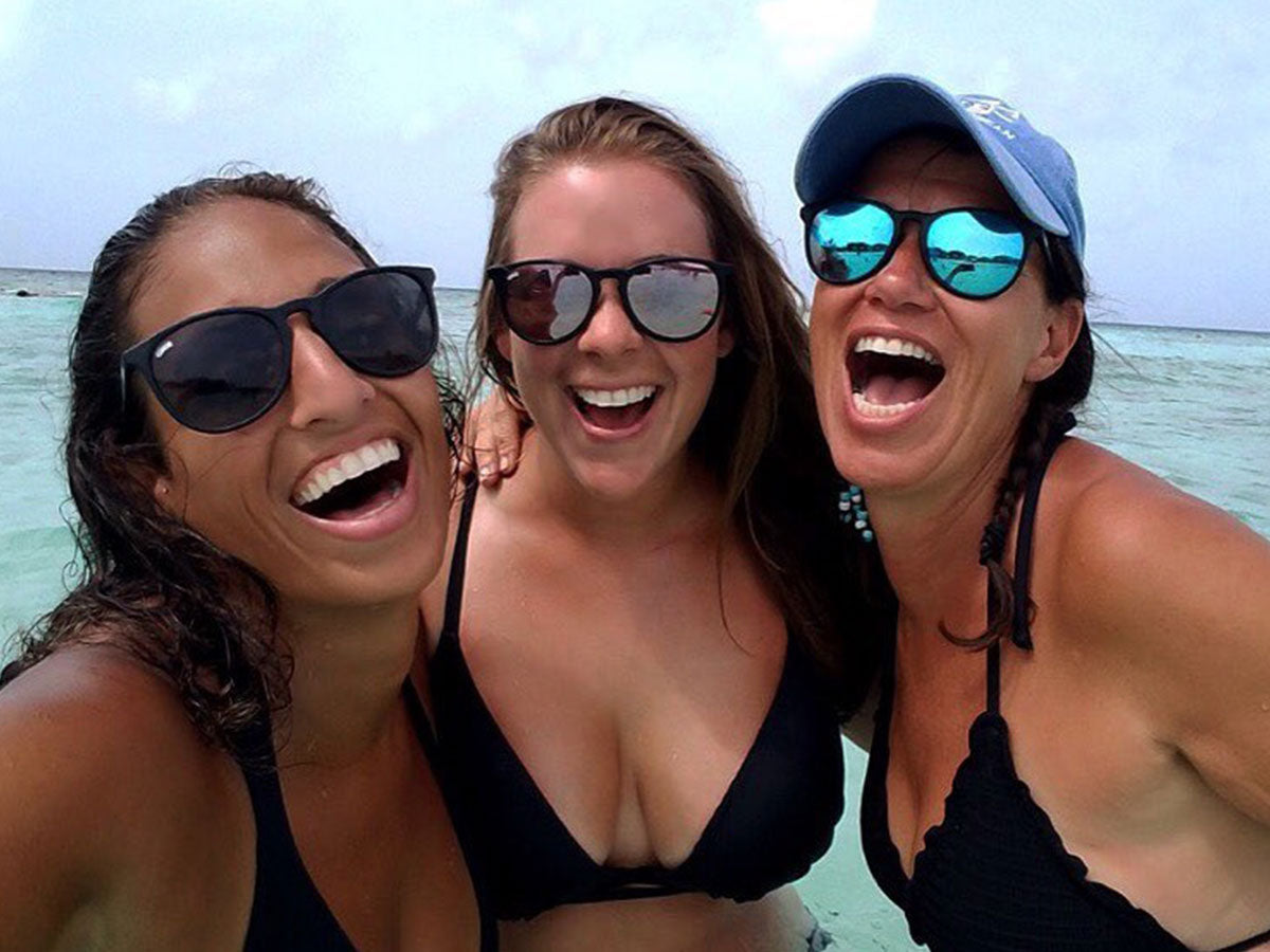 three women wearing sunglasses in the ocean